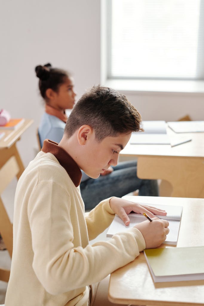 Two students focused on writing notes in a bright classroom setting.